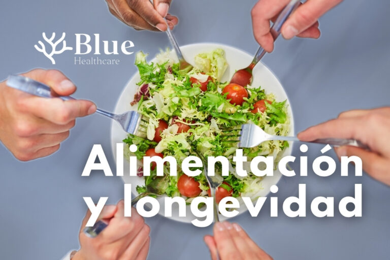 Manos de varias personas compartiendo una ensalada de vegetales frescos con aceite de oliva, símbolo de una alimentación equilibrada y rica en fibra, asociada a la longevidad y la salud metabólica.